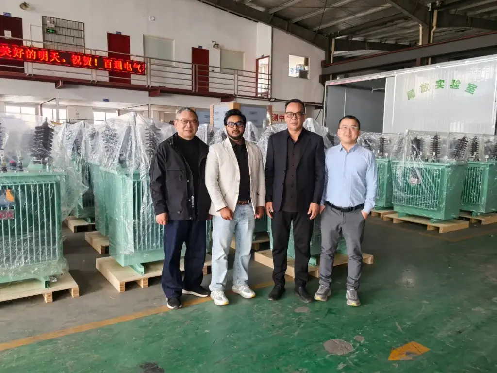Baitong Electric factory in Yueqing with multiple packaged oil immersed transformers, showing foreign client inspection and local team.
