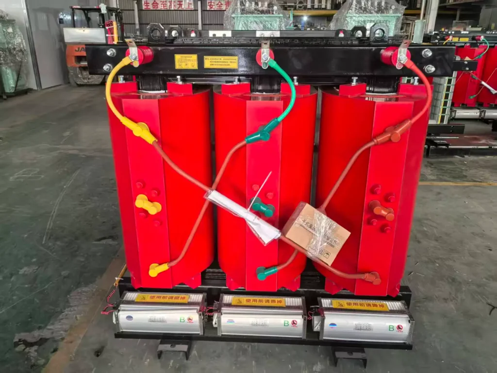 Red epoxy cast resin coils and cooling fans of a dry type transformer on the factory floor, built by outdoor dry type transformer manufacturer Baitong Electric, ready for enclosure integration.