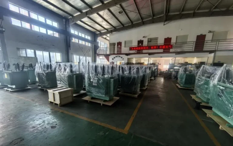 Dozens of green transformers wrapped in plastic on wooden skids ready for dispatch inside the Baitong Electric 1000 kva oil immersed transformer factory.