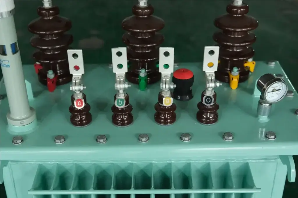 A close-up view of essential oil immersed transformer components including high voltage bushings, tap changer, and gauges on the Baitong Electric factory floor.