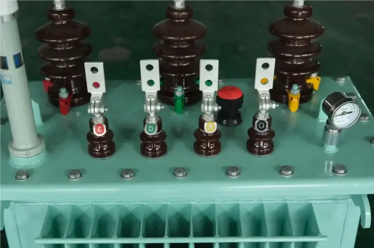 A close-up view of essential oil immersed transformer components including high voltage bushings, tap changer, and gauges on the Baitong Electric factory floor.