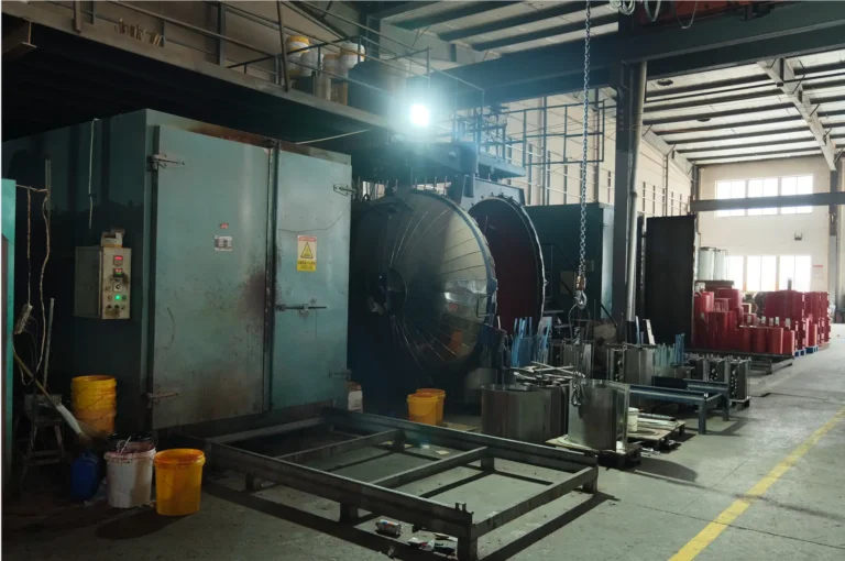 A heavy-duty industrial workshop featuring a massive vacuum chamber and curing ovens used in the professional resin casting for dry type transformers at the BTCN factory.