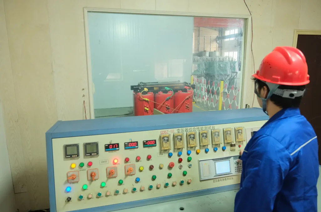A Baitong Electric technician wearing a red hard hat conducting rigorous testing of dry type transformer using an advanced control console inside the factory laboratory.