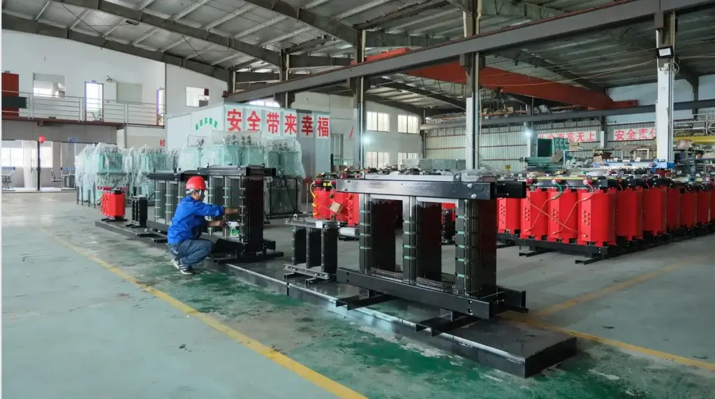 A Baitong Electric technician assembling a magnetic core next to red cast resin coils, demonstrating why we use dry type transformer technology for maximum safety.