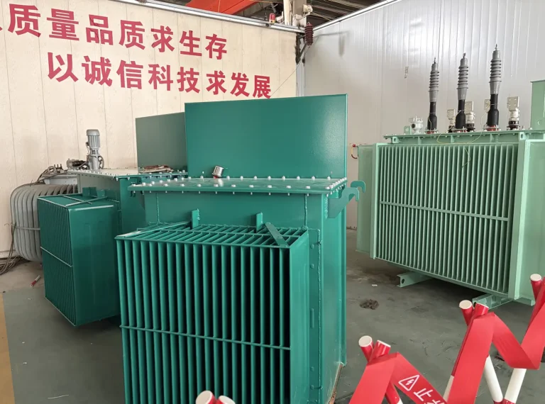 Green 10kv oil immersed transformers sitting on the factory floor behind a red safety barrier at the Baitong Electric manufacturing center.