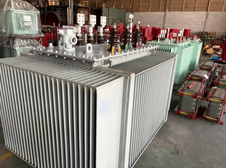 A gray china oil immersed transformer with corrugated cooling fins in the foreground, with stacked silicon steel cores and factory production lines visible in the background.