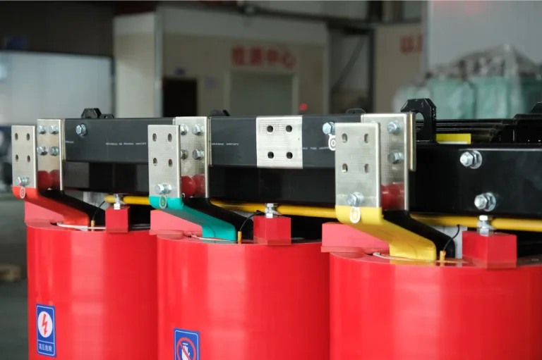 A close-up view of color-coded dry type transformer connection terminals and red cast resin coils on the Baitong Electric factory floor.