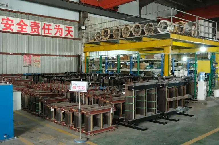 Dozens of assembled magnetic units in the dry-type transformer core production area at the Baitong Electric factory, showing massive manufacturing capacity and raw steel material storage.