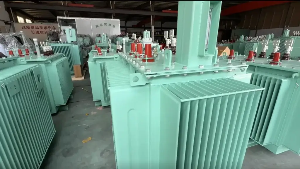 A batch of newly manufactured mint-green 75 kVA oil filled transformers with red insulators and corrugated cooling fins on the Baitong Electric factory floor.