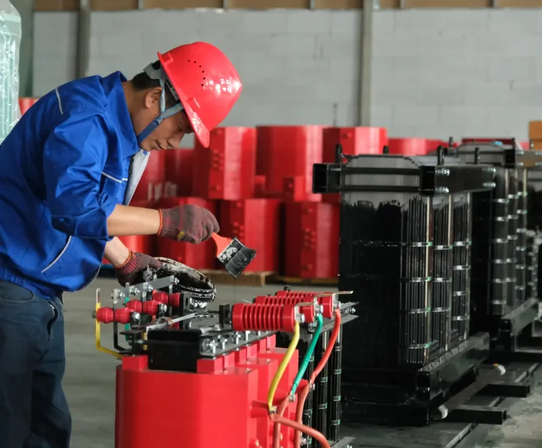 A Baitong Electric worker in a red hard hat painting the internal steel frame of a cast resin transformer, showcasing premium dry type transformer manufactures.