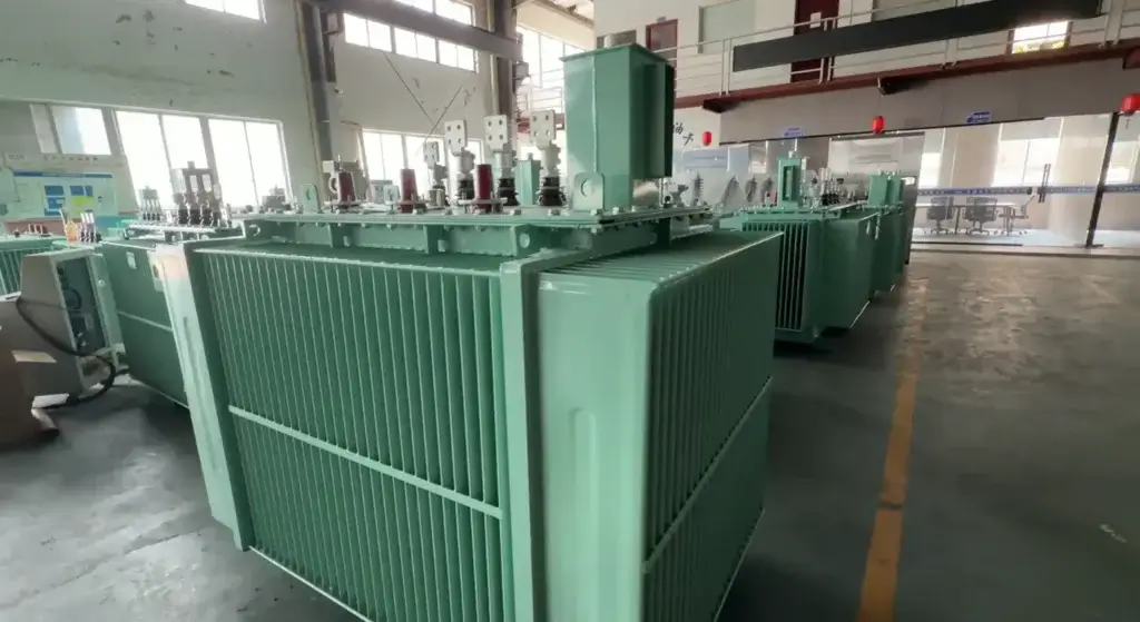 A row of mint-green transformer oil immersed type units with corrugated cooling fins on the Baitong Electric factory floor.