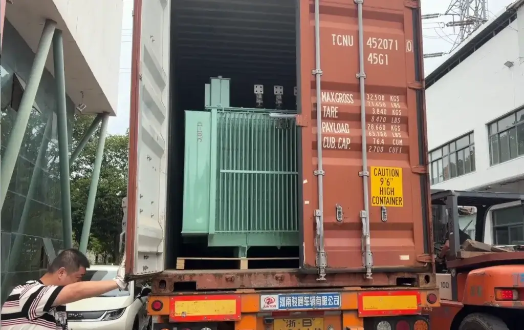 Baitong Electric factory workers using a forklift to load a green oil-immersed unit into a high cube transformer shipping container.