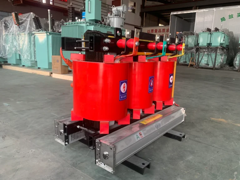 Three-phase dry-type transformer with red resin-insulated windings and base-mounted cooling fans in the BTCN Electric workshop