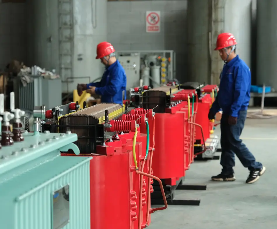 Two BTCN factory workers beside red cast resin dry type transformer assemblies in the workshop